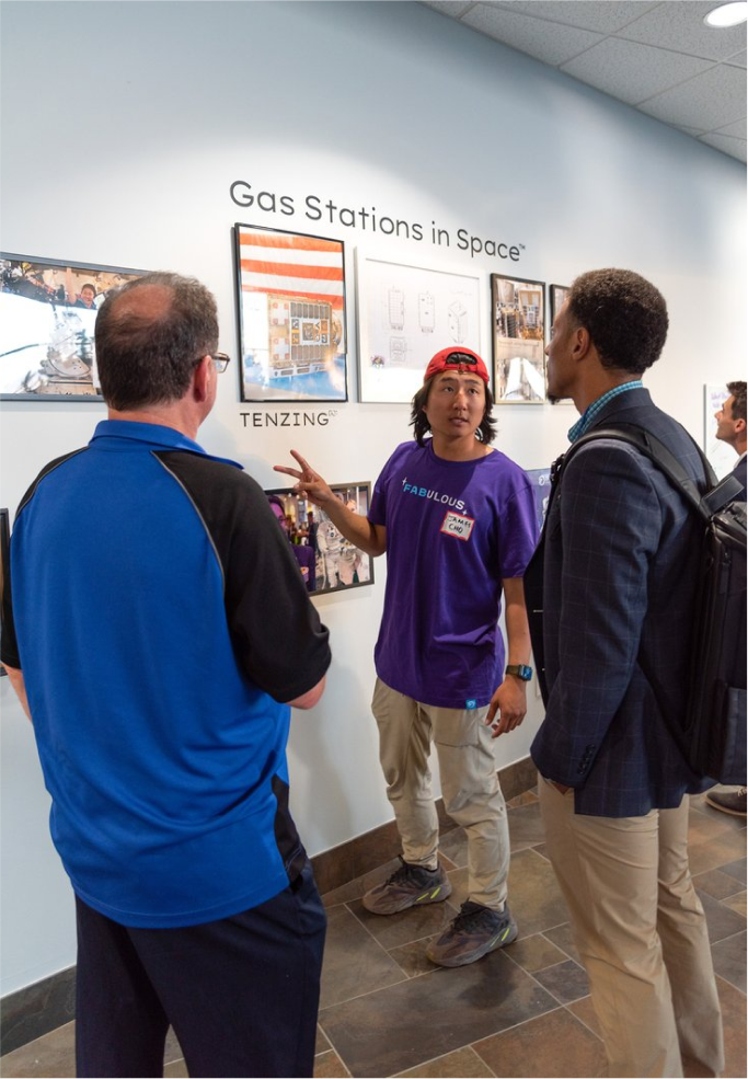 Three people talking about photographs on a wall