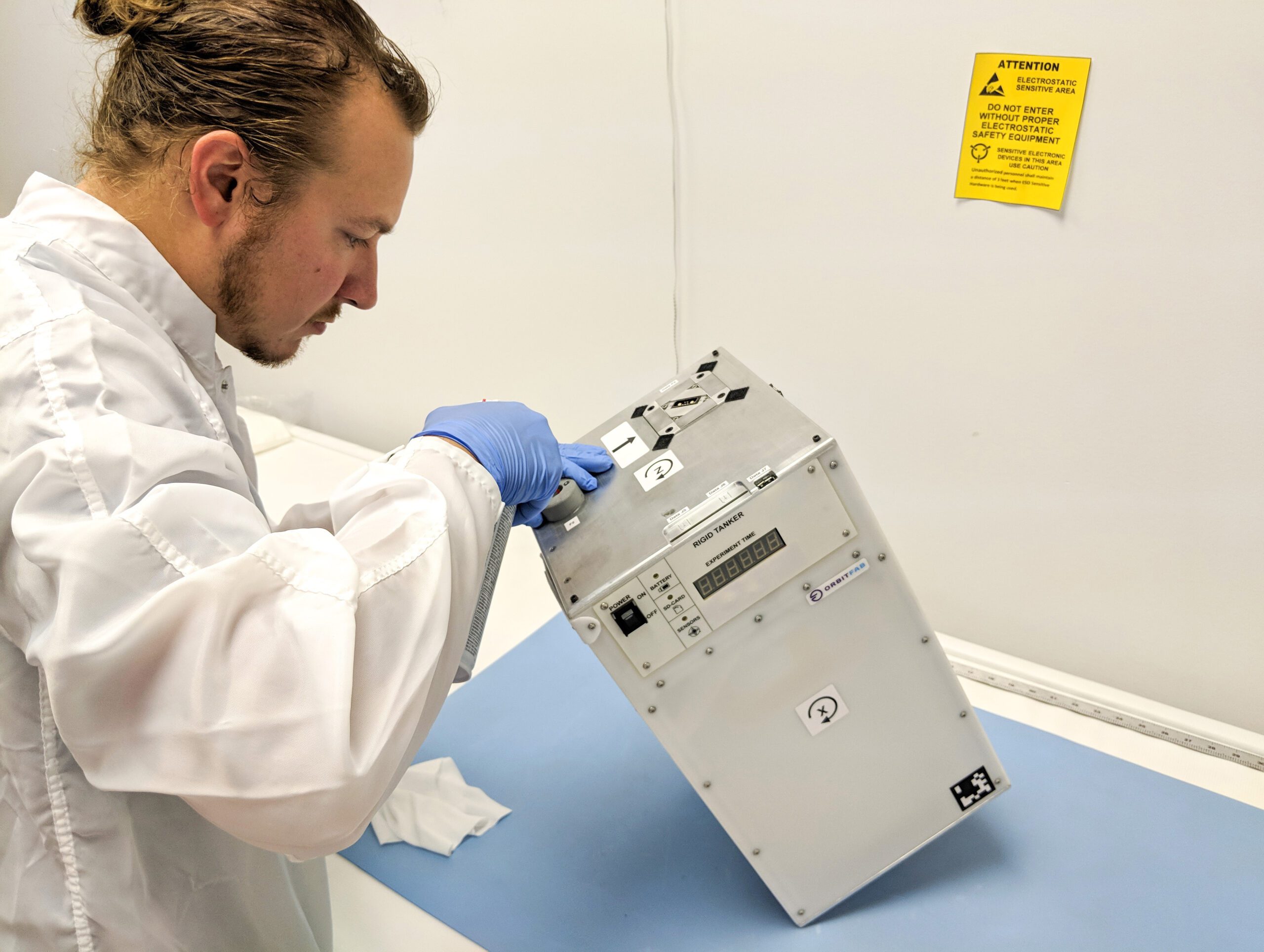 Person working on a spacecraft in a cleanroom