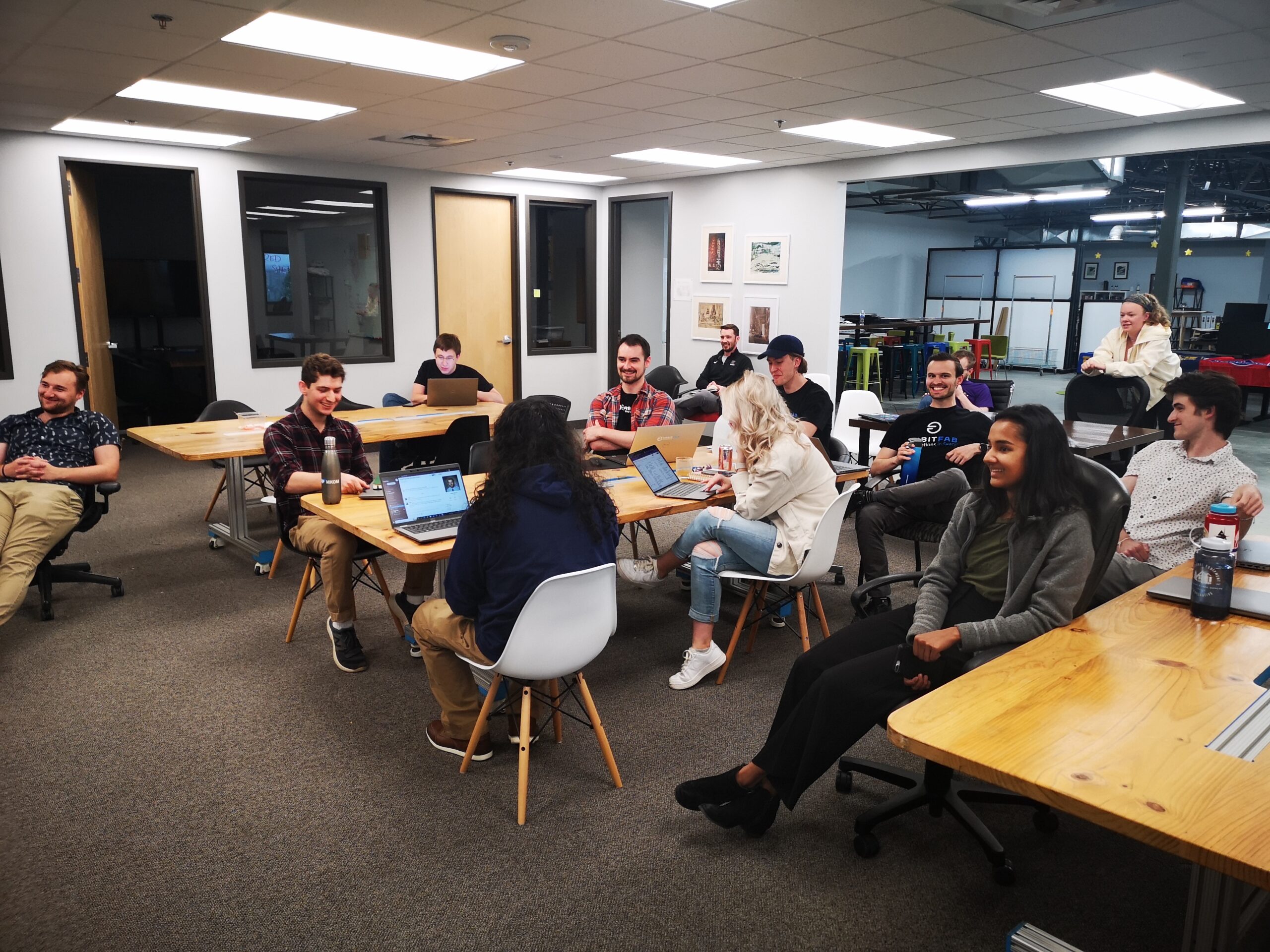 Several people in a large room around tables having a meeting