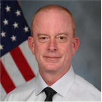 Headshot of man with American flag in background