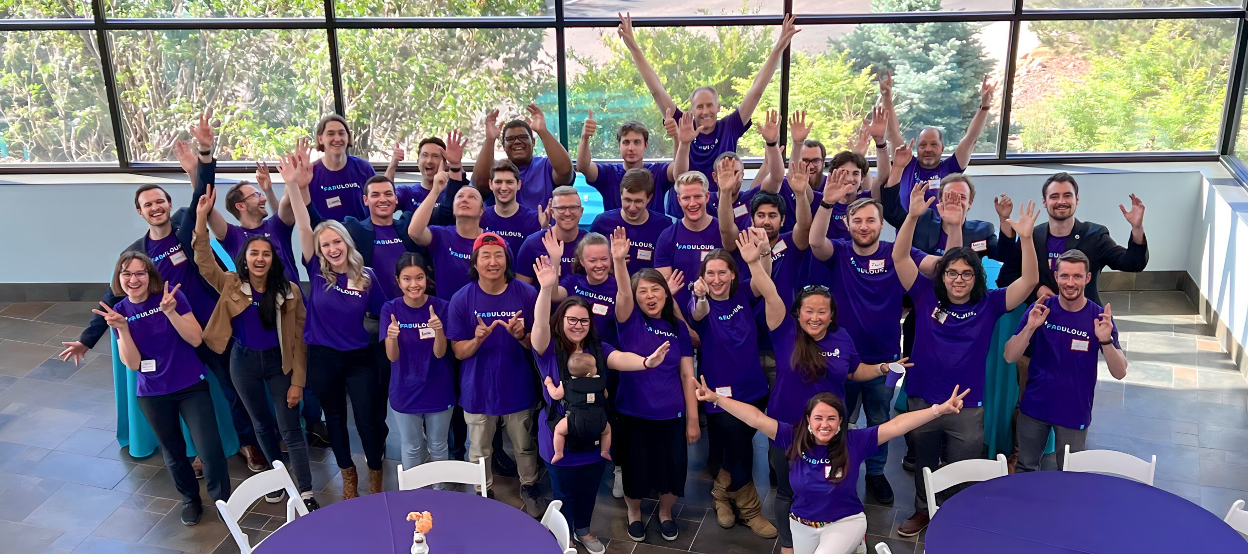Orbit Fab team wearing purple "Fabulous" shirts stands with hands outstreached.