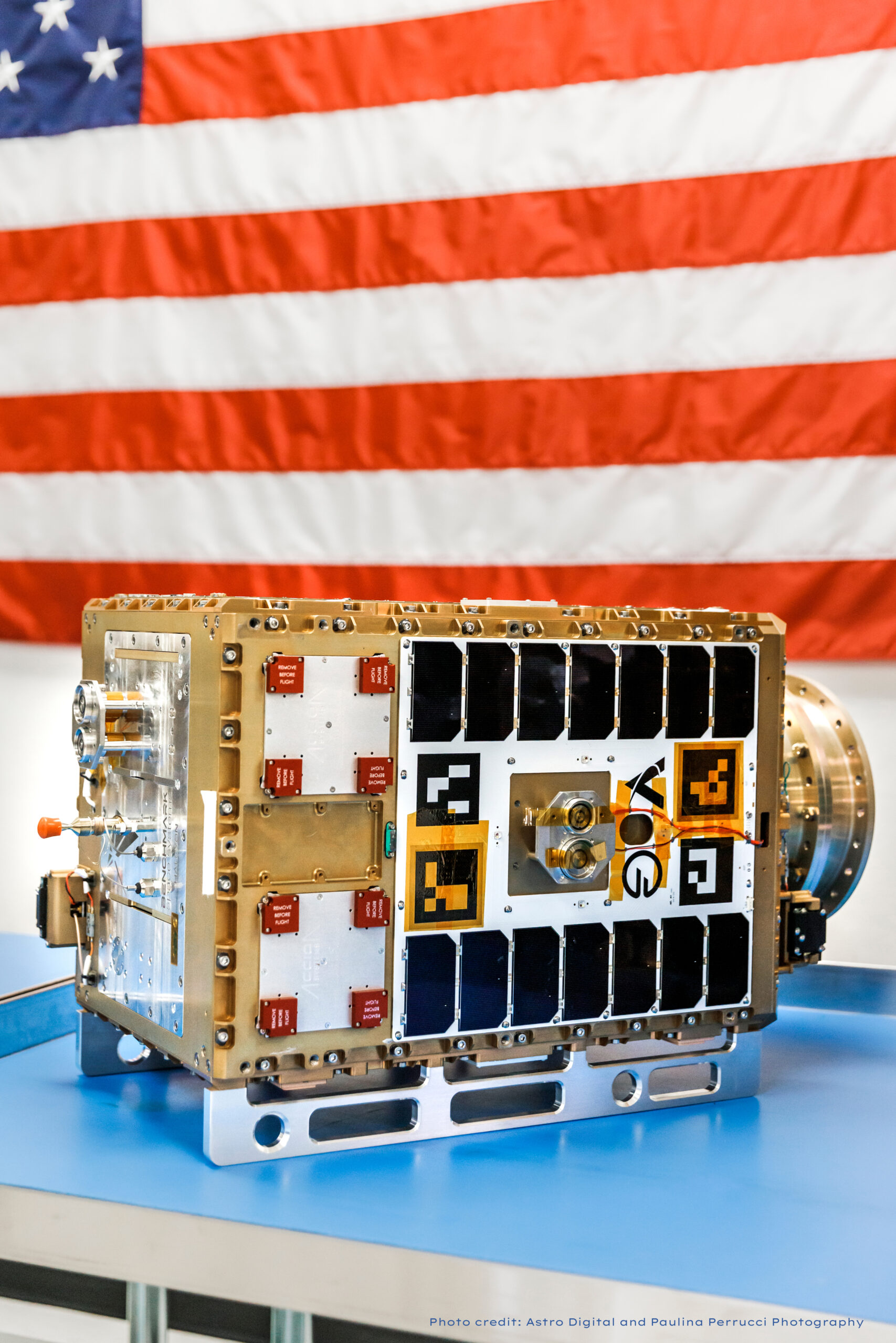 Orbit Fab Tenzing spacecraft on blue surface with American flag in background