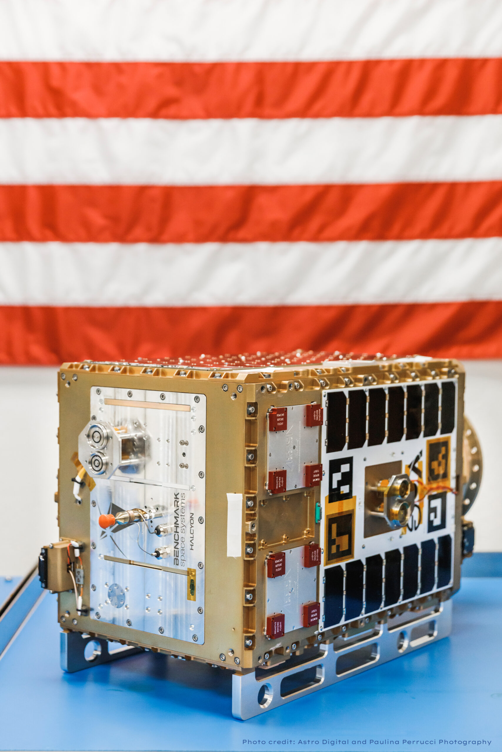 Orbit Fab Tenzing spacecraft on blue surface with American flag in background