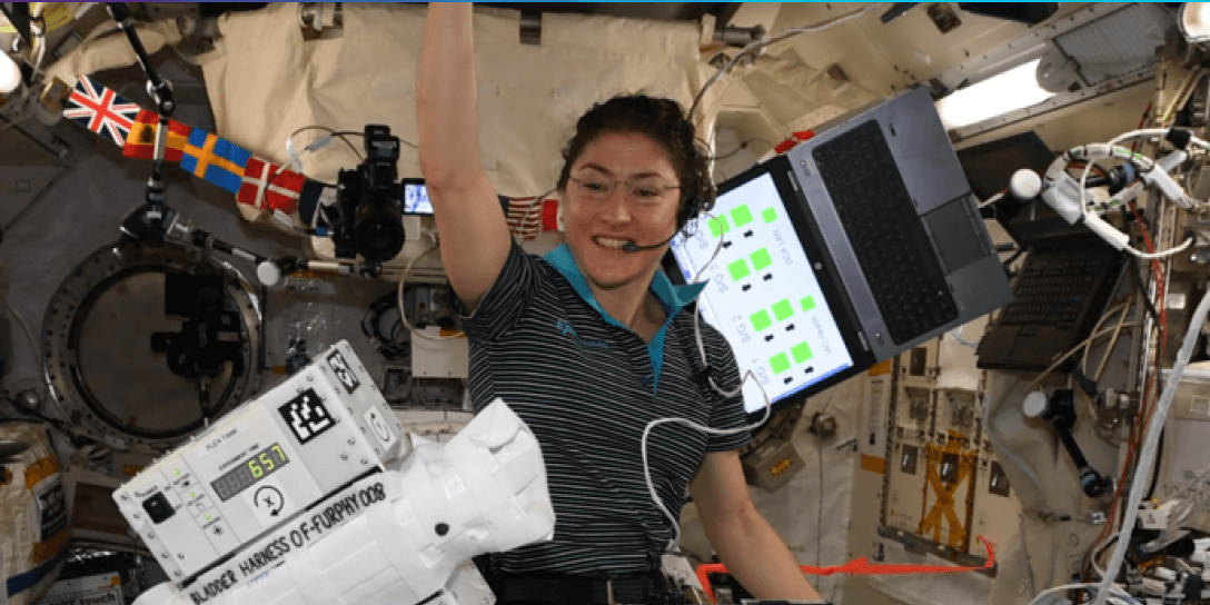 Astronaut Christina Koch onboard the ISS with Orbit Fab's FURPHY payloads floating in front of her